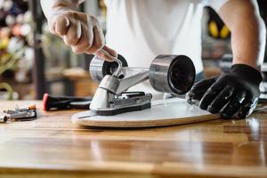 man use the socket tool or hex keys to remove the nuts on skateboard and adjusts suspension in workshop, Skateboard maintenance and repair concept. Selective focus photo