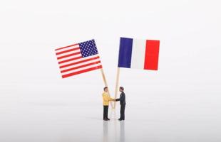 dos hombres de negocios dándose la mano frente a banderas de francia y estados unidos foto