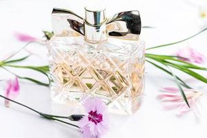 A bottle of women's perfume with pink carnation flower on a white background photo