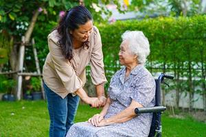 Caregiver help Asian elderly woman disability patient sitting on wheelchair in park, medical concept. photo