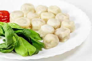 Boiled dumplings with spinach and tomato sauce photo