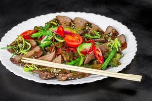 Baked vegetables and beef with chopsticks