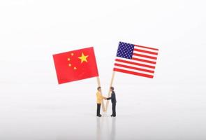 dos hombres de negocios dándose la mano frente a banderas de estados unidos y china sobre fondo blanco foto