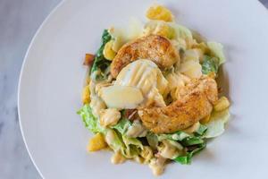 Caesar salad with fresh green vegetable is mixed with grilled chicken, boiled white egg and crispy bread. It is a healthy food concept. photo