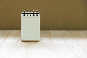 simulacros de papel de cuaderno pequeño o soporte de bloc de notas en una mesa de madera para escribir información con espacio de copia foto