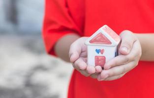 Small kid hands holding house photo