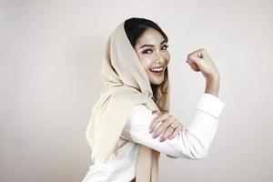 Gorgeous strong young Muslim woman isolated over white background wall showing biceps. photo