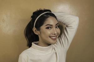 Smiling young Asian woman tying her hair. Haircare. Beauty concept. photo