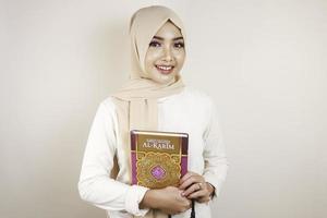 Young Asian Muslim woman smiling and holding the Quran photo