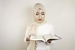 Young Asian Muslim woman wearing head scarf reading the Quran photo