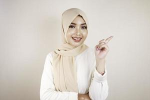 Cheerful young Muslim Asian woman pointing side to copy space with smile photo