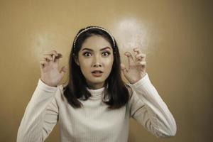 Beautiful Asian girl is mad and angry with arms fist isolated on orange background. photo