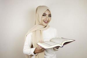 Young Asian Muslim woman smiling and holding the Quran photo