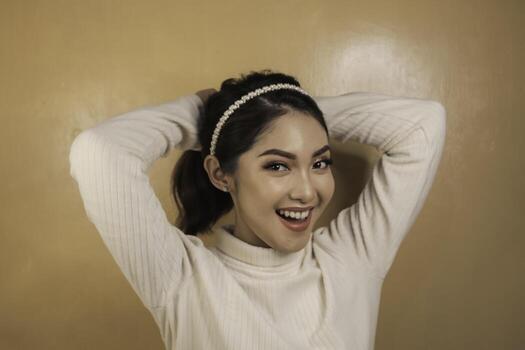 sonriente joven asiática atándose el pelo. cuidado del cabello. concepto de belleza. foto