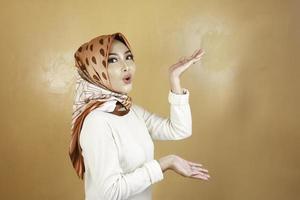 Shock face of young Muslim Asian woman pointing side to copy space photo