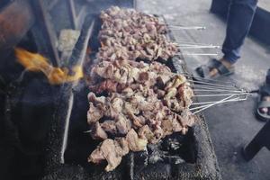Proceso de fabricación de satay klathak de cabra cruda en una parrilla de carbón. foto