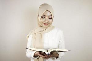 Young Asian Muslim woman smiling and holding the Quran photo