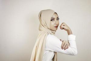 hermosa mujer musulmana joven fuerte aislada sobre la pared de fondo blanco que muestra bíceps. foto