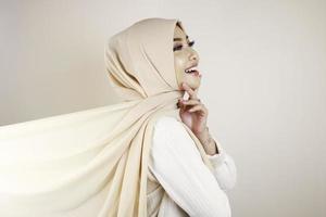 mujer musulmana con ropa tradicional y hiyab aislada de fondo blanco. el hiyab se hace volando de forma creativa. concepto de moda idul fitri e hijab. foto
