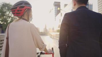 dos caminando juntos a casa después del trabajo durante la puesta de sol, opción de transporte alternativa, evitando el tráfico de la ciudad, empujando la bicicleta de camino al trabajo, teniendo una conversación positiva mientras caminan video