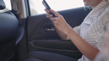 una adolescente asiática disfruta usando una aplicación móvil sentada en un camión familiar, una bella dama deslizándose en las redes sociales mirando nuevas fuentes de sus amigos mientras se relaja, la tecnología y el concepto de la vida cotidiana video