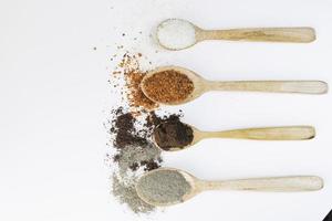Various spices on wooden spoons on white background photo