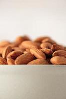 Almonds in ceramic bowl on white wood table.organic Diet raw material photo