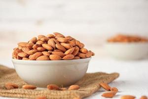 Almonds in ceramic bowl on white wood table.organic Diet raw material photo