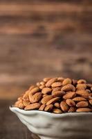 Almonds in wood bowl on wood table.Diet raw material