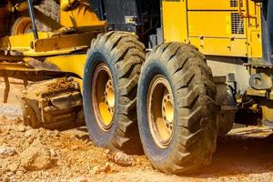 niveladora de carreteras que trabaja en el sitio de construcción para el mantenimiento y la construcción de caminos de tierra y grava. motoniveladora amarilla. Maquinaria pesada y equipos de construcción para nivelación de caminos. máquina niveladora. foto