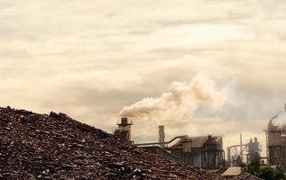 Pile of brown bottle for recycle in recycling factory. Glass waste for recycle. CO2 emissions. Carbon dioxide greenhouse gas emissions from factory chimneys. Smoke from chimneys. Air pollution concept photo