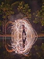 Fire show and reflections from the water surface with the trees on the background. photo