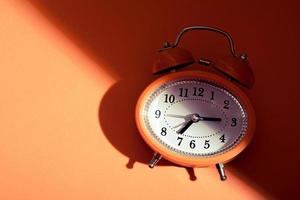 Vintage style alarm clock under the bright light and dark shadow. New day coming concept. photo