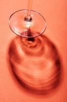 naturaleza muerta minimalista, copa de vino sobre fondo rojo con sombra creativa. foto