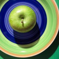 manzana verde en un plato colorido con sombra oscura. granny smith manzana verde en un plato. foto