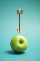 Abstract still life concept a levitating key and a green apple. Education and wisdom concept. photo