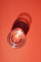 Glass of water with abstract dark shadow on red background. photo