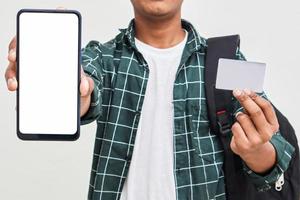 estudiante universitario indio mostrando pantalla móvil y tarjeta sobre fondo blanco. foto