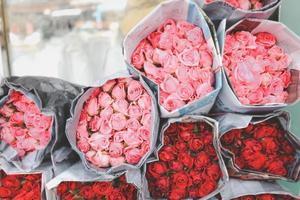 hermosa rosa colorida envuelta en papel a la venta en el mercado de las flores, regalo presente en el día de san valentín.