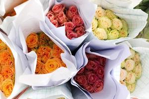 hermosa rosa colorida envuelta en papel a la venta en el mercado de las flores, regalo presente en el día de san valentín. foto