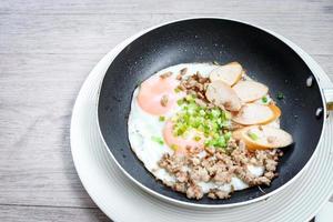 Pan-fried egg with toppings, hot breakfast in cooking served on table in morning. photo