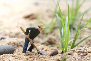 Miniature worker doll holding shovel for working, miner man at work tiny figure toy model digging ground or gardening photo