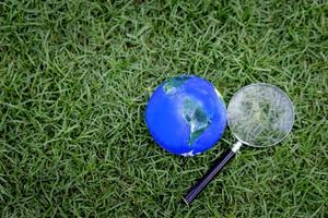 Earth globe with magnifying glass on green grass, discovering new things on our planet, interested in nature and the world photo