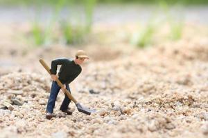 muñeca de trabajador en miniatura sosteniendo una pala para trabajar, hombre minero en el trabajo modelo de juguete de figura diminuta cavando tierra o jardinería foto