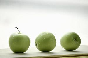 fruta cruda de manzana verde madura con gota de agua sobre mesa de madera, productos frescos orgánicos saludables foto