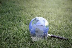 Earth globe with magnifying glass on green grass, discovering new things on our planet, interested in nature and the world photo