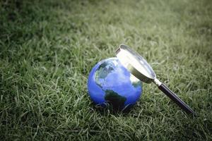 Earth globe with magnifying glass on green grass, discovering new things on our planet, interested in nature and the world photo