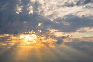 rayos naranjas del sol a través de nubes cumulus en el cielo al atardecer en verano. luz mágica celestial. foto