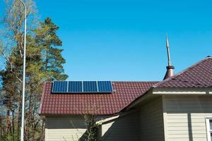 Solar panels on the roof of a private one-story house in the countryside. Eco-friendly use of solar energy, an alternative source. Caring for nature, resource conservation photo