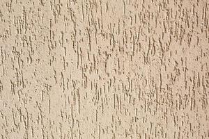 Plaster on the wall with a bark beetle pattern of beige and sand color. Background, texture. Exterior decoration of building, house. photo